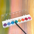 A set of metallic watercolor paints with swatches of color displayed next to a paintbrush, all arranged on a white background.