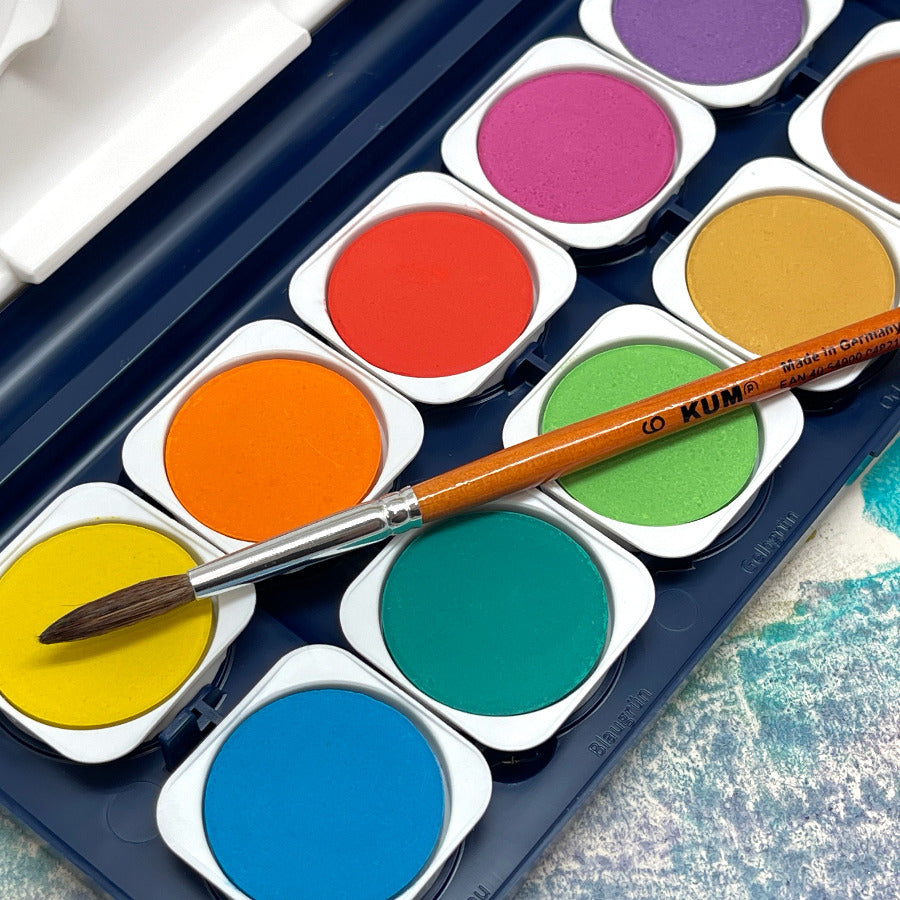 Close up of colorful watercolor paint set with a paintbrush