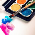 Close up of colorful watercolor painting testing colors of paint set with paintbrush