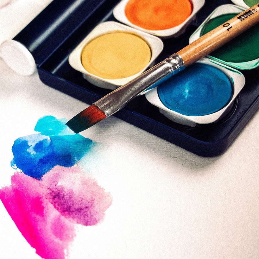 Close up of colorful watercolor painting testing colors of paint set with paintbrush