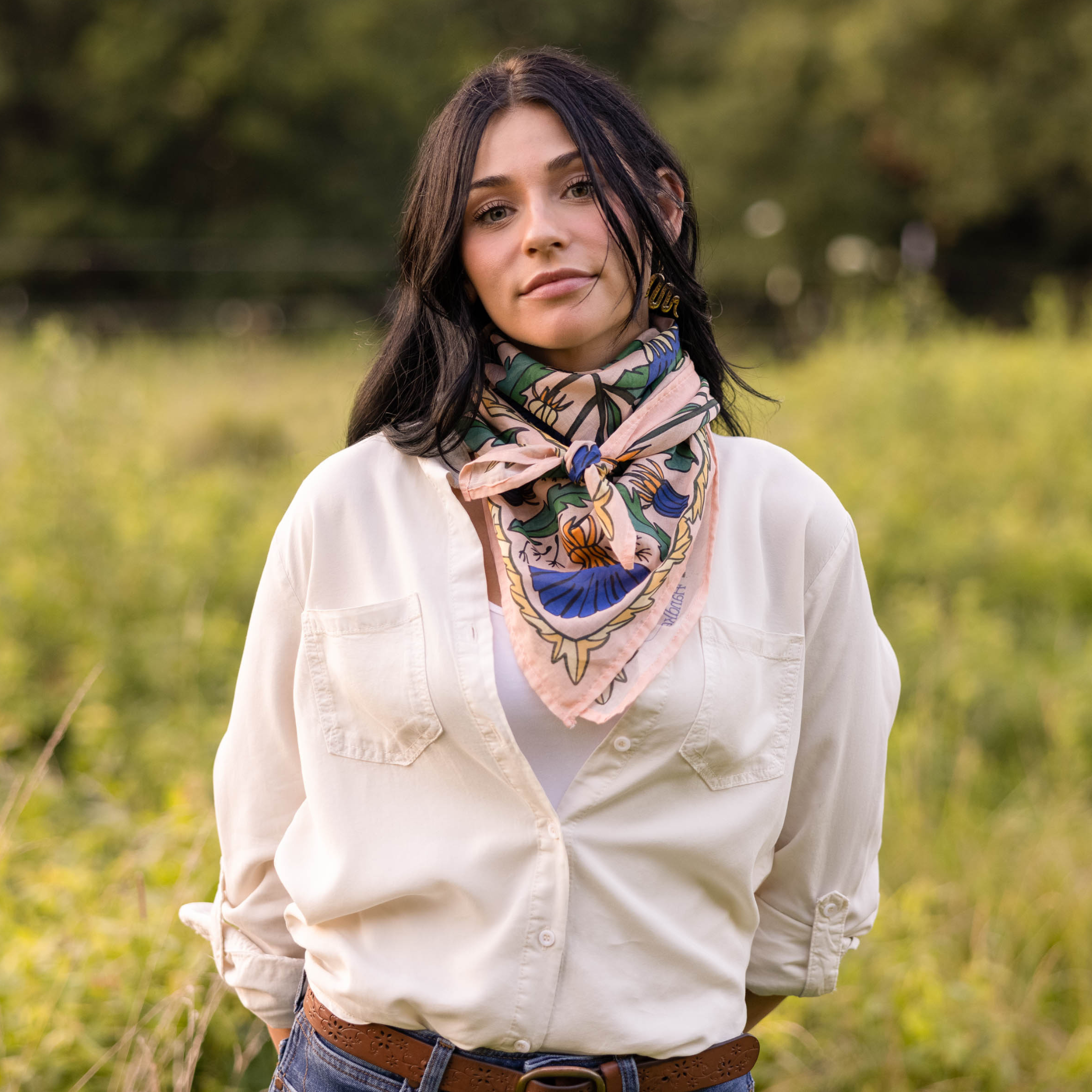 Woman wearing a pink fabric dandelion flower patterned scarf in a field