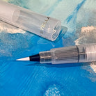 Glitter shimmer brush tip pen with clear ink on a blue background