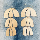 Pair of handmade earrings in gold-tone textured brass on a denim background