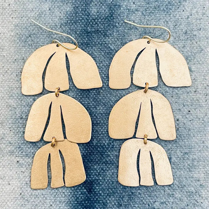 Pair of handmade earrings in gold-tone textured brass on a denim background