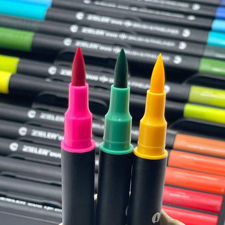 Pink, green and yellow brush pens with colorful markers in a set in the background