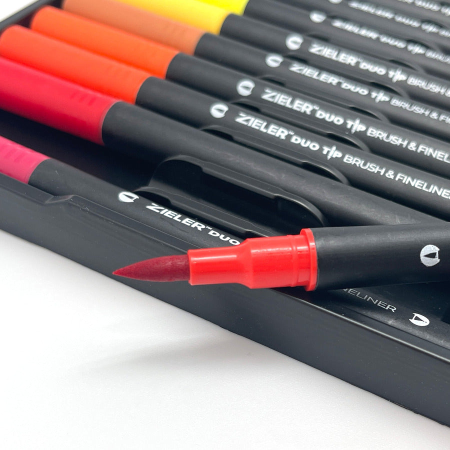 Close up of red brush tip pen with other colored duo tip markers in the background