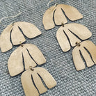 Close up of handmade brass earrings on textured background