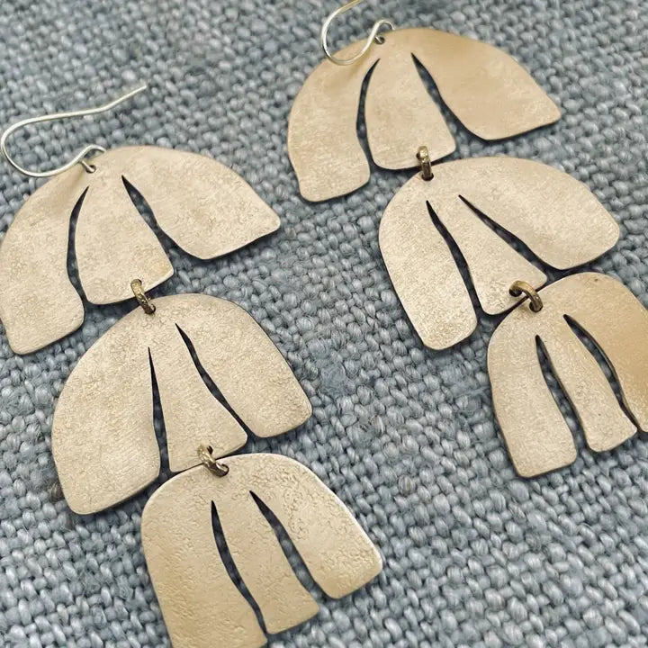 Close up of handmade brass earrings on textured background