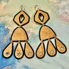 pair of gold-tone handmade brass teardrop earrings with black thread stitched edges on a muted color background