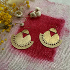Gold earrings on a textured fabric surface with yellow flowers.