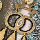 Textured brass handmade earrings with two hares dancing and color thread edges on a muted background
