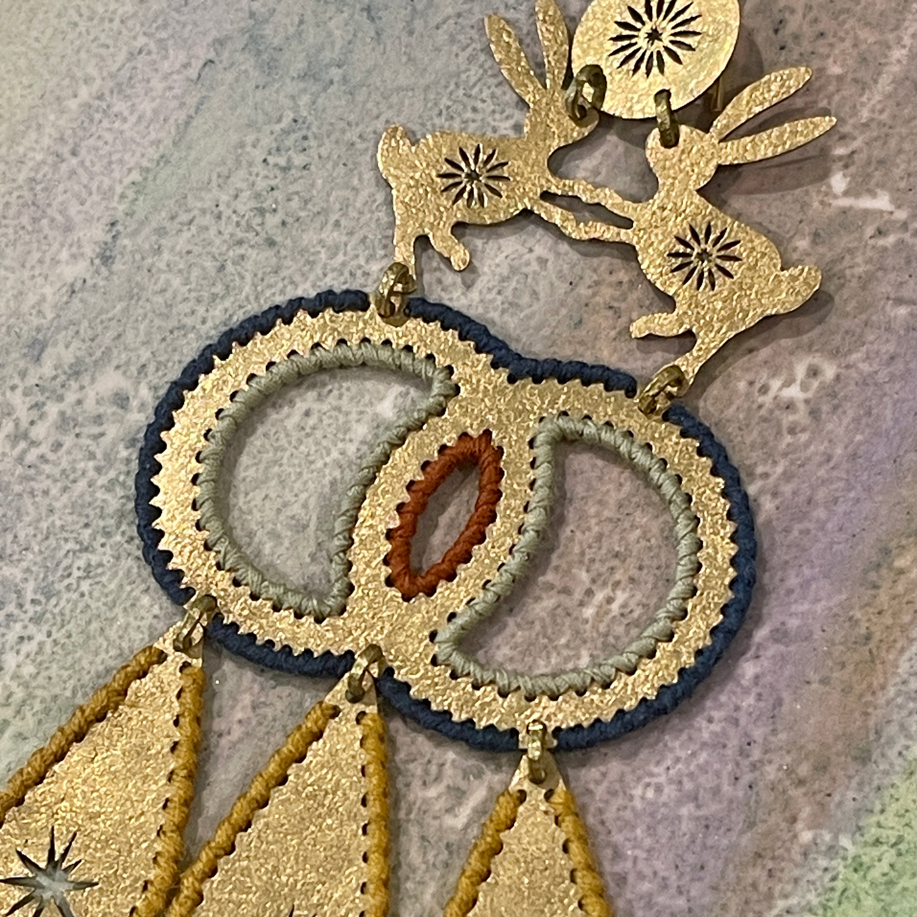 Textured brass handmade earrings with two hares dancing and color thread edges