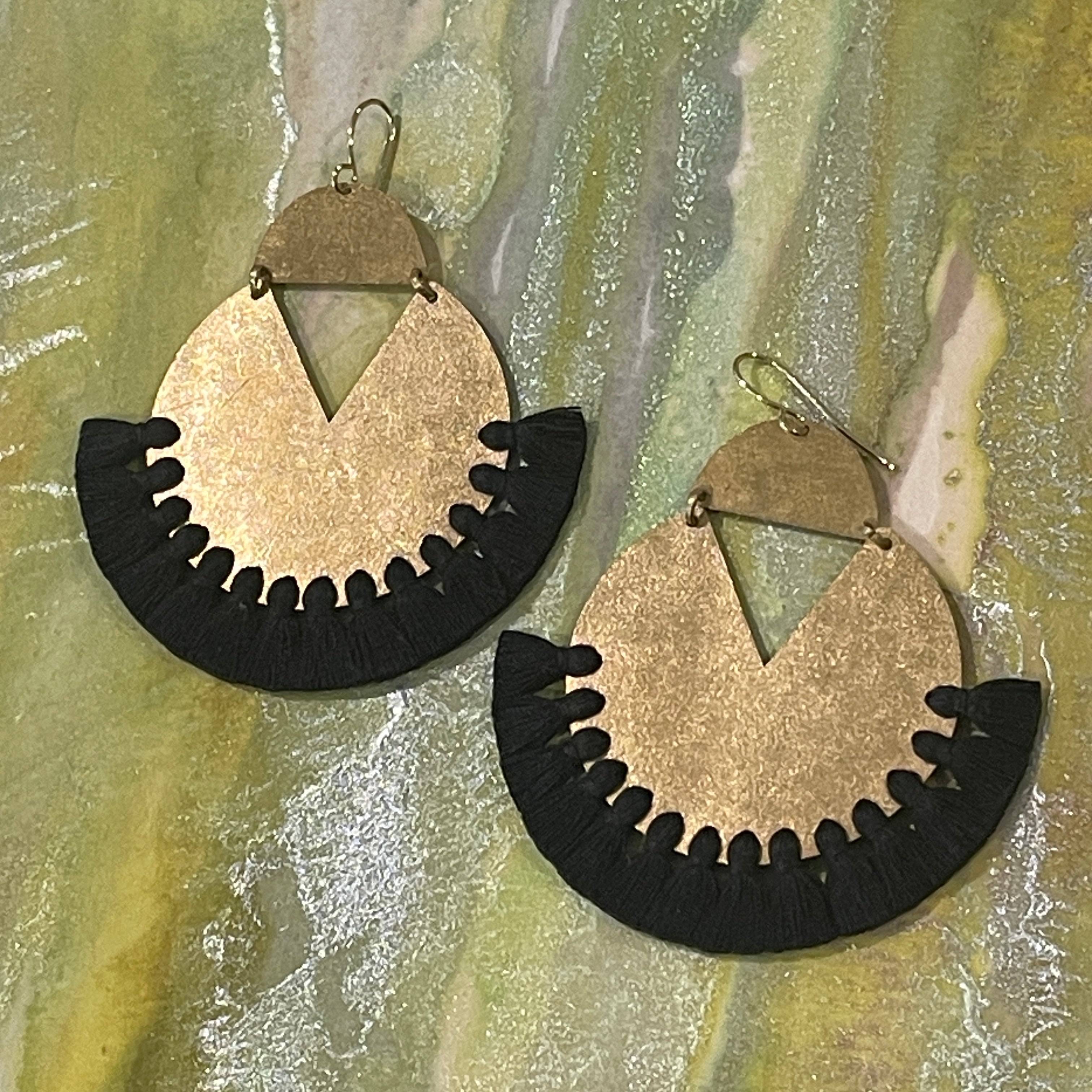 Pair of handmade brass dangle earrings with black color thread fringe detail on a metallic painting background