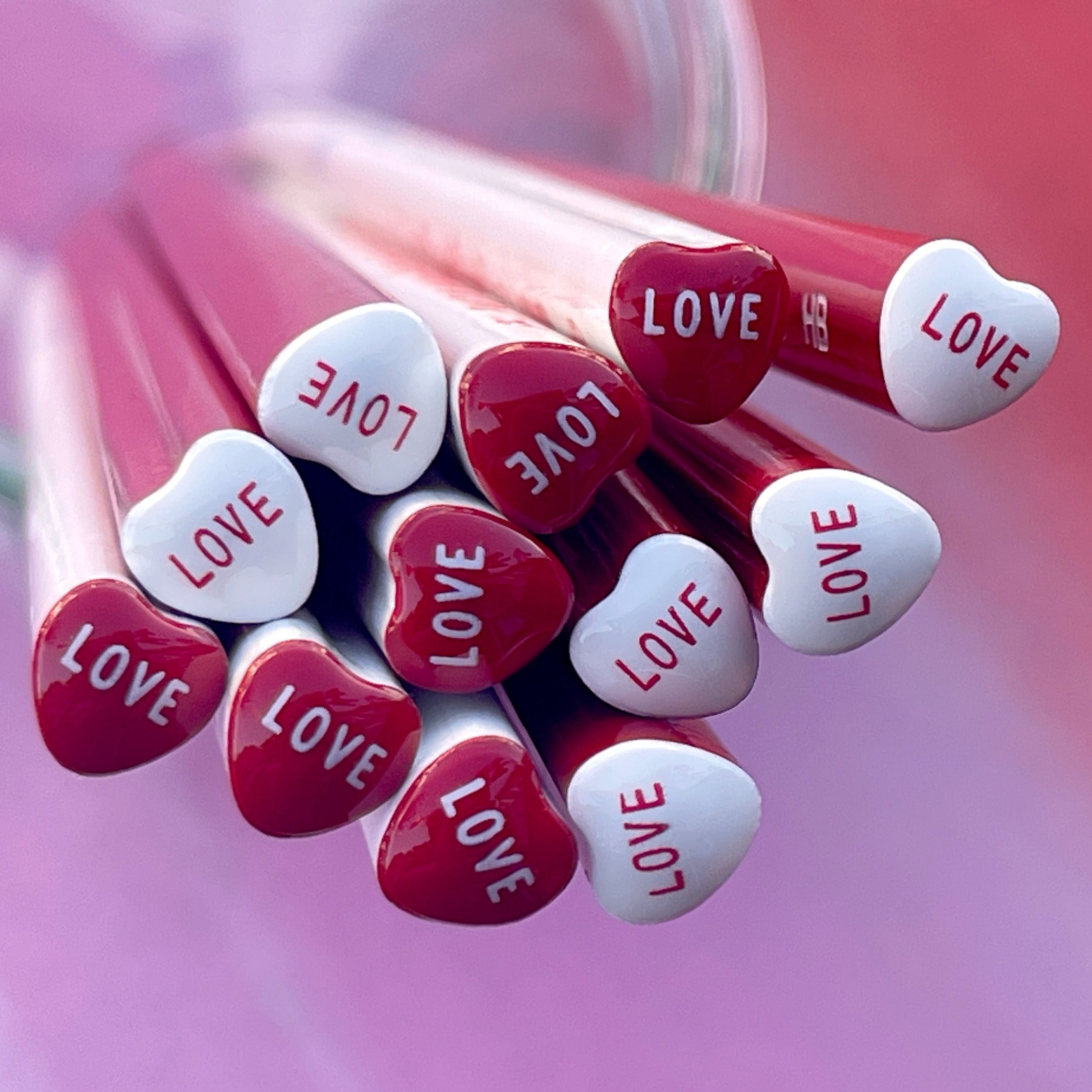 Red heart-shaped pencils with 'LOVE' text on a pink background