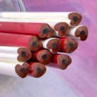 Red and white heart shape pencils with wooden tips on a pink background