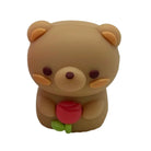 A small brown teddy bear pencil sharpener holding a red tulip flower with green leaves, shown on a plain white background.