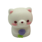 A small white bear-shaped pencil sharpener with pink inner ears, dark brown eyes and nose, pink cheeks, and a purple tulip flower with a green stem held in front of its chest, shown on a plain white background.