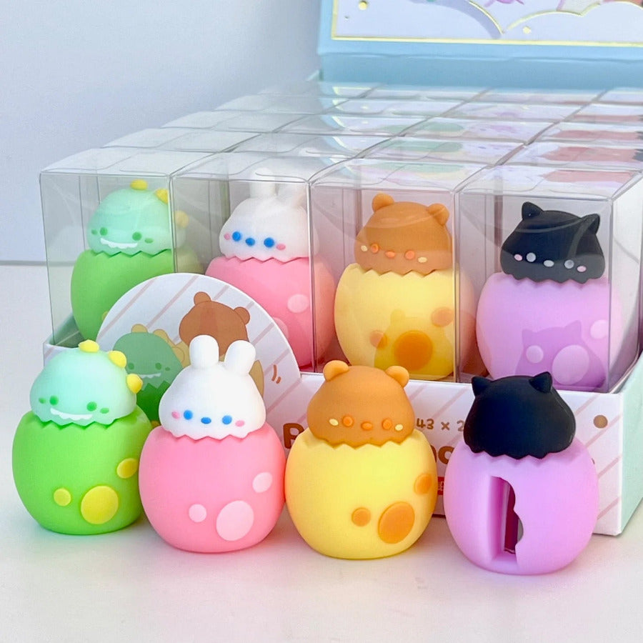 Several hatching animals in eggs -  dinosaur, a bunny, a bear, and a black cat pencil sharpeners in a display