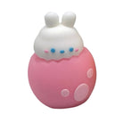 A small white bunny with blue eyes in a pink egg pencil sharpener, shown on a plain white background.
