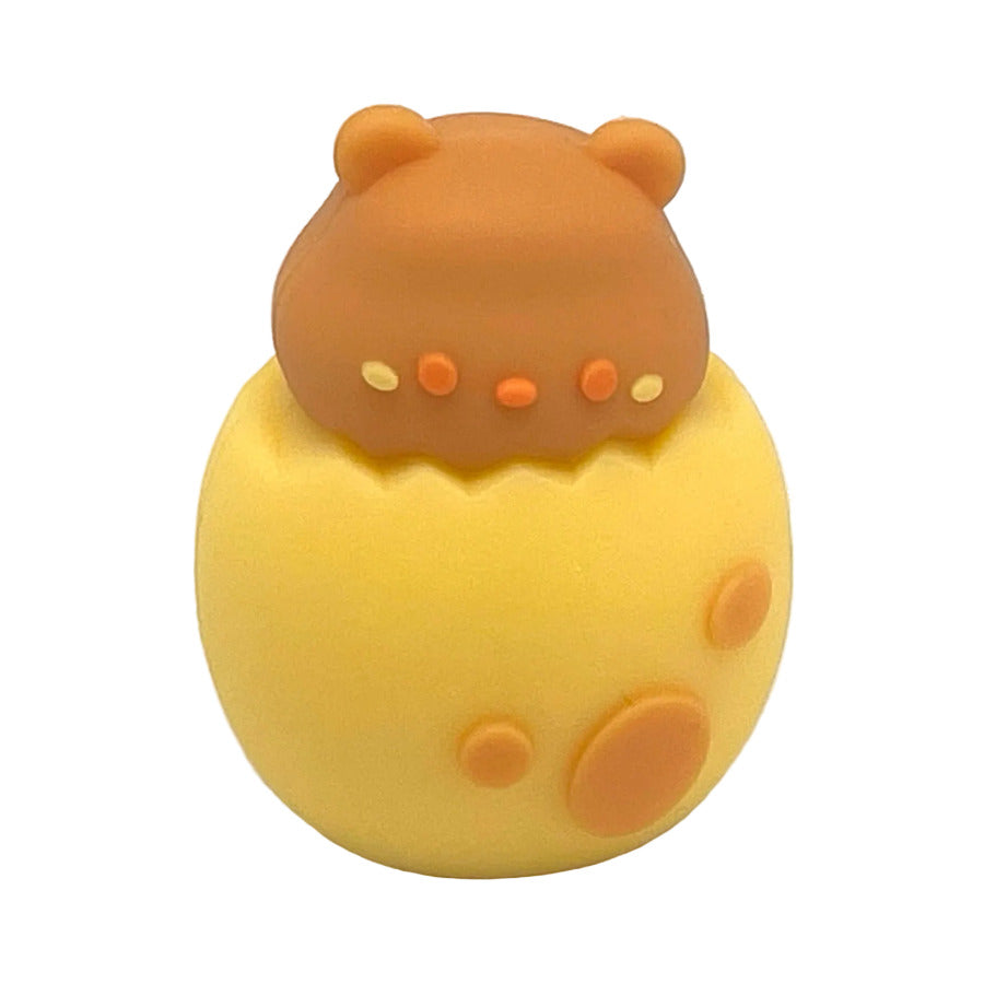 A cute, small brown bear sitting inside a cracked yellow egg pencil sharpener, set against a plain white background.