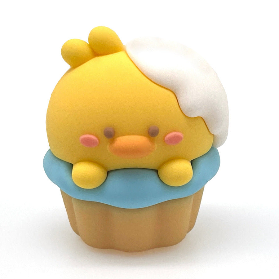 A small cupcake-shaped pencil sharpener with a yellow chick face and body, white frosting, and a cupcake base, centered on a plain white background.