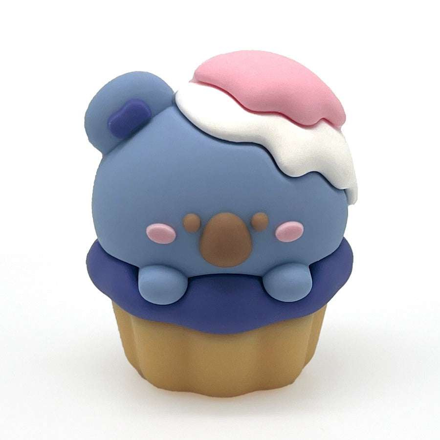 A small cupcake-shaped pencil sharpener with a blue koala bear face and white and pink frosting, and a cupcake base, centered on a plain white background.