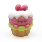 A cute, stylized cupcake pencil sharpener with a pink bunny face peeking out from white frosting, topped with a pink bow, sitting on a light green frosting layer over a tan base, set against a plain white background.