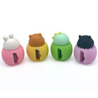Four cute egg shaped pencil sharpeners with baby animal heads lined up in a row on a white background. From left to right, they have a pink rabbit head, a yellow bear head, a green dinosaur head, and a purple cat head.