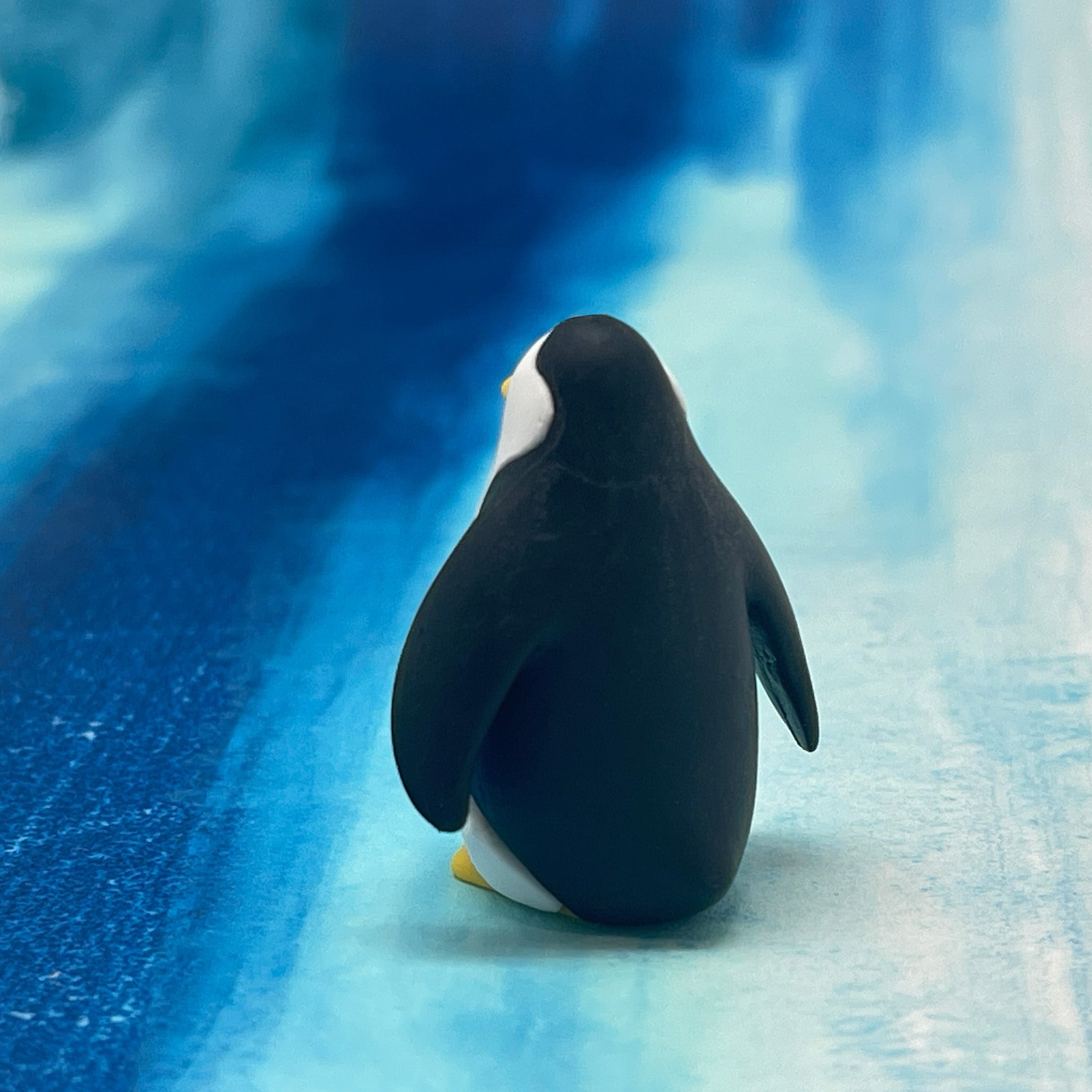 Back of a penguin eraser on a blue and white textured surface