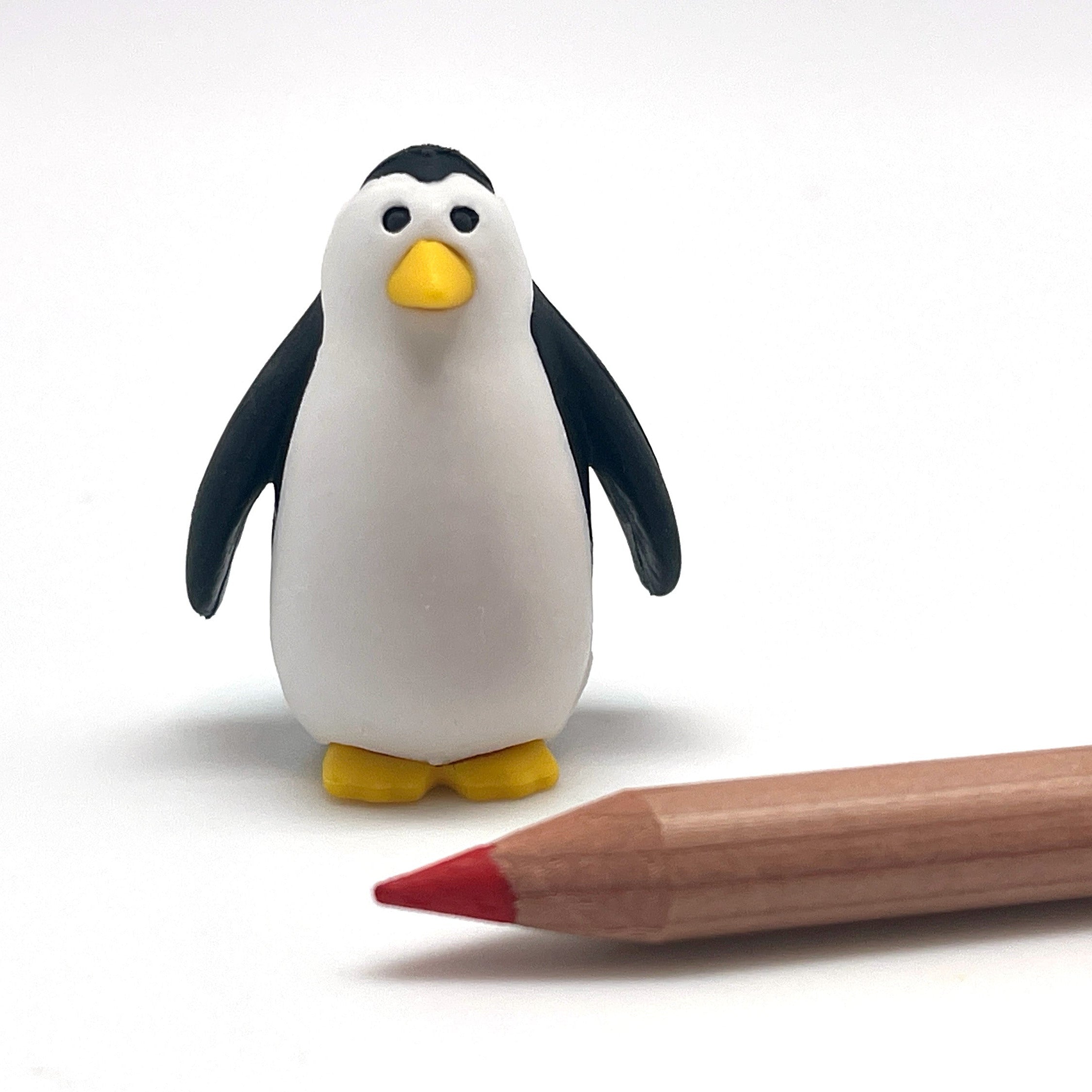 Penguin eraser next to a wooden pencil on a white background