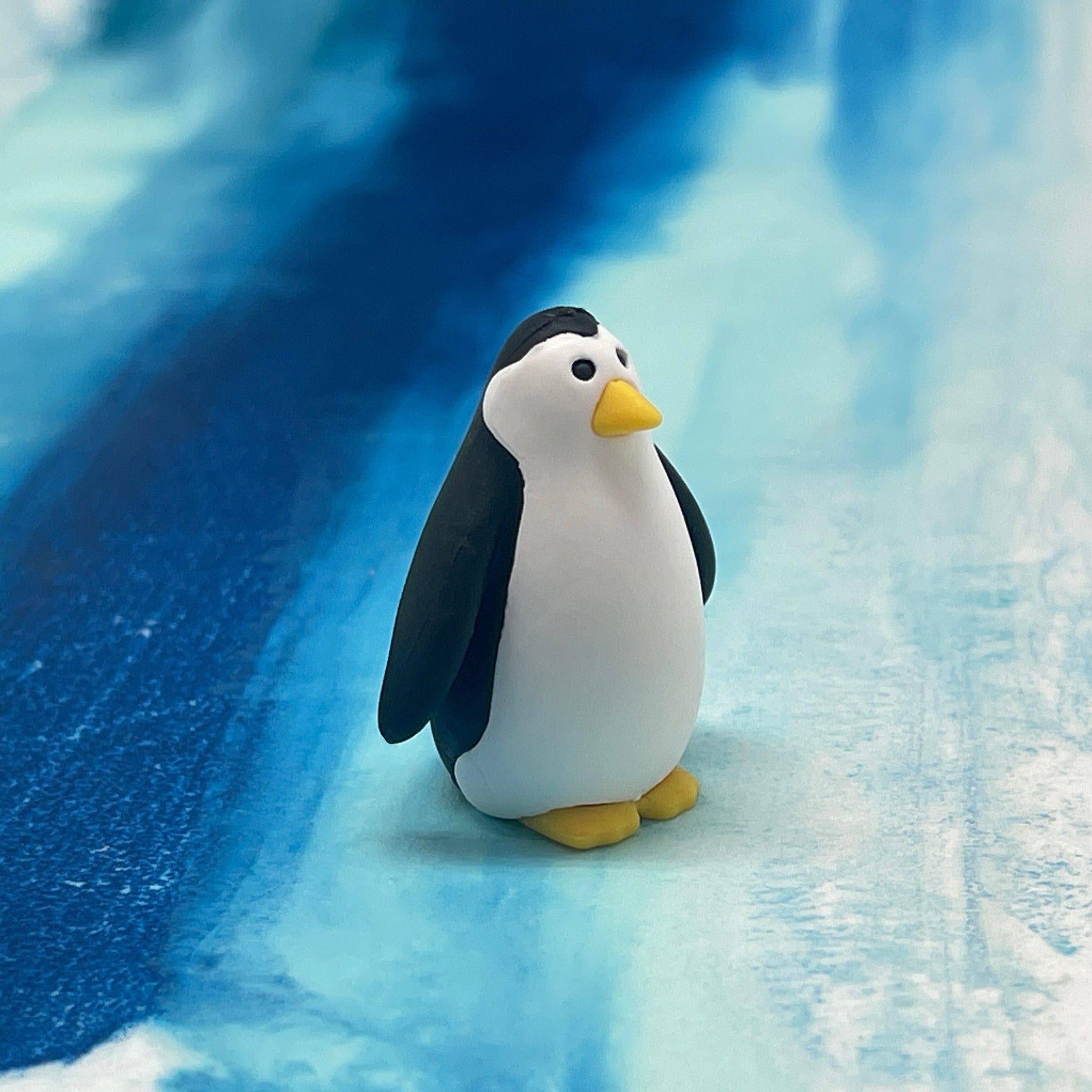 Penguin figurine standing on a blue and white textured surface