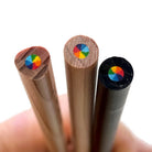 Three wooden rainbow pencils showing the multi-color core with  7 colors swirl in 1 pencil, held in a hand against a white background.