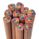 A dozen cedar wood pencils viewed from above, showing the end detail with 7-in-1 multi-color rainbow swirl core. The pencils have a warm brown wood grain and are set against a plain white background.