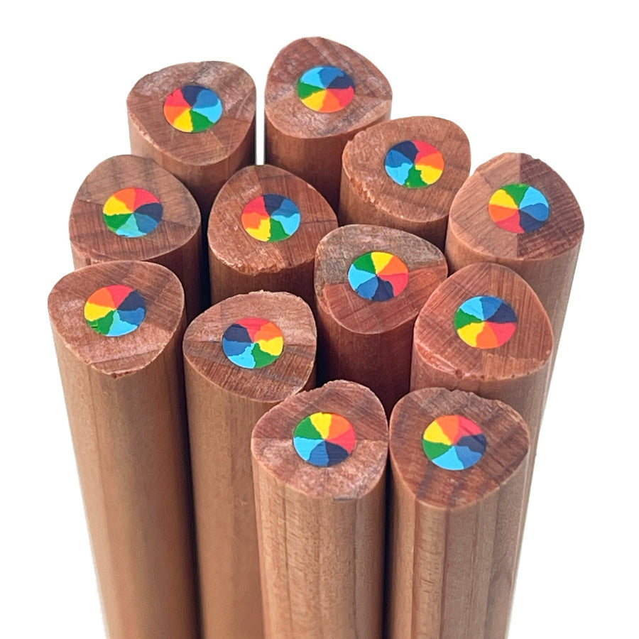A dozen cedar wood pencils viewed from above, showing the end detail with 7-in-1 multi-color rainbow swirl core. The pencils have a warm brown wood grain and are set against a plain white background.