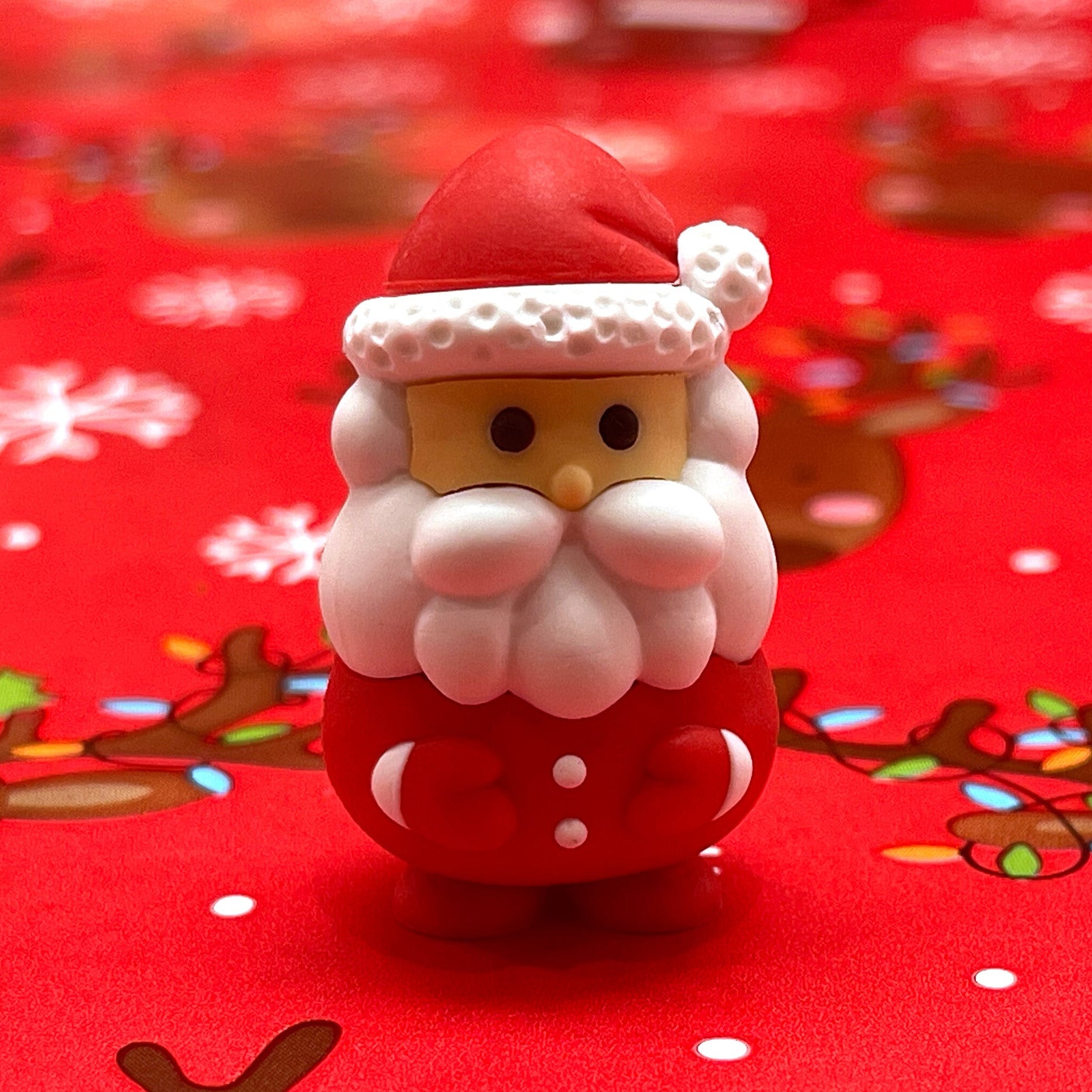 Mini Santa eraser on a red Christmas theme background with reindeer and snowflakes
