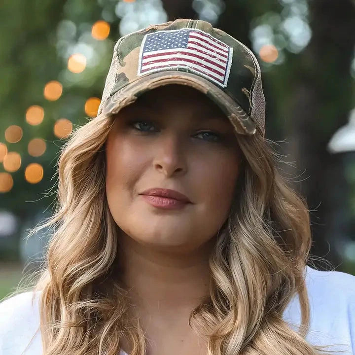 Woman wearing a camouflage cap with an American flag patch outdoors