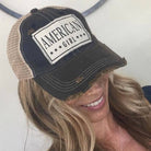 Woman wearing a navy blue cap with 'American Girl' patch on a white background