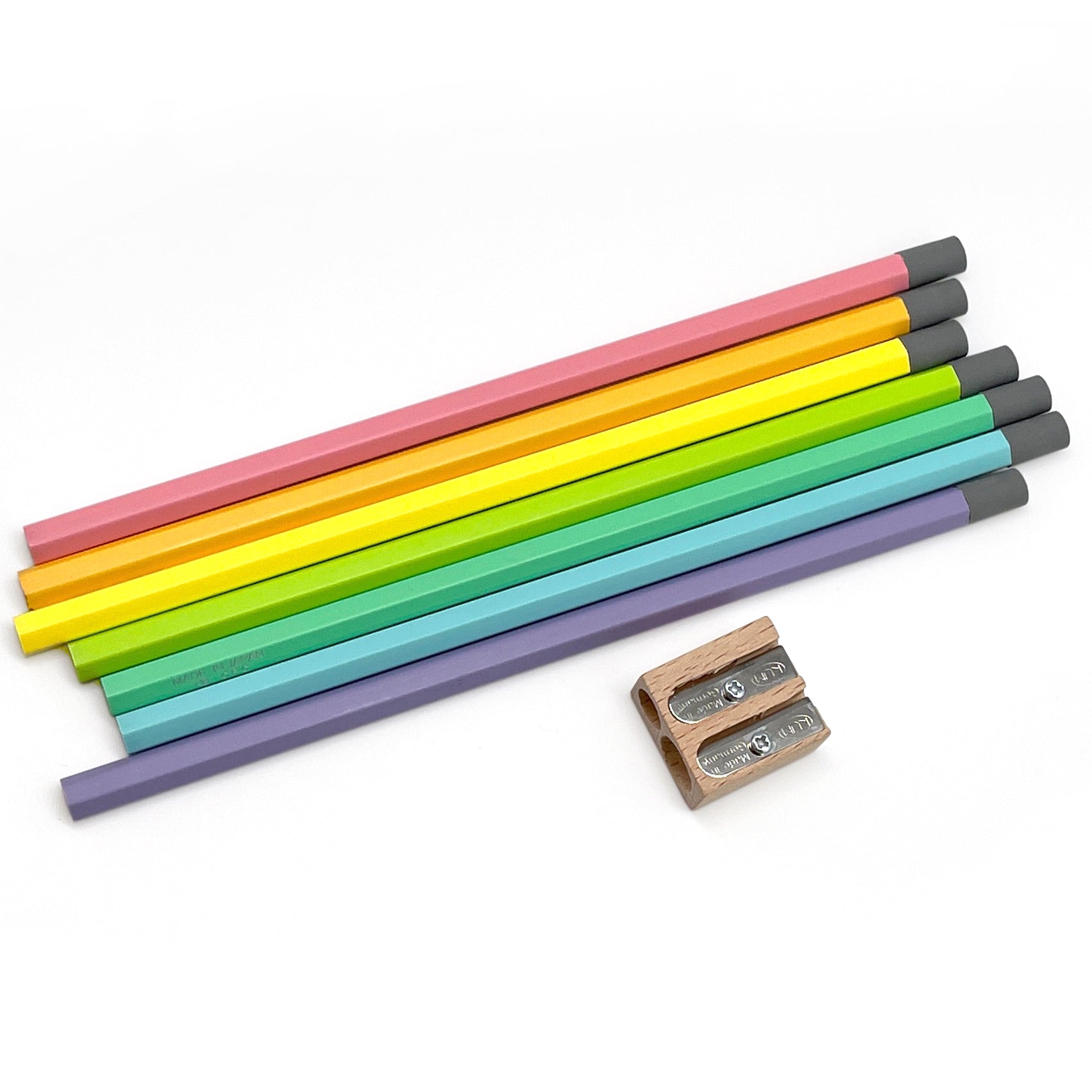 A set of multicolored wooden pencils with pastel colors, including pink, green, yellow, blue, and purple, alongside a wooden sharpener.